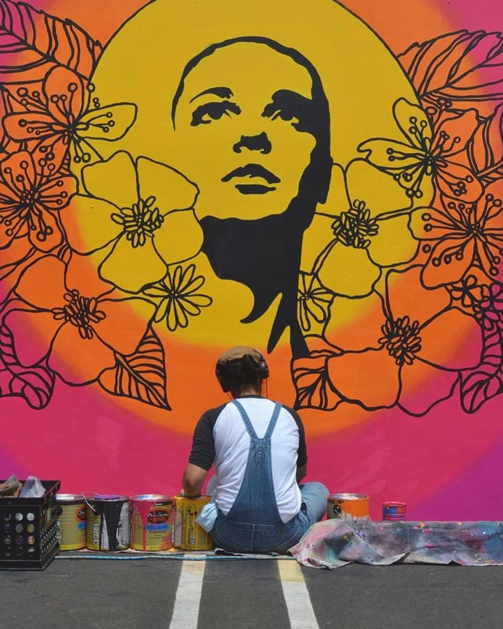 Un joven con un graffiti en la pared