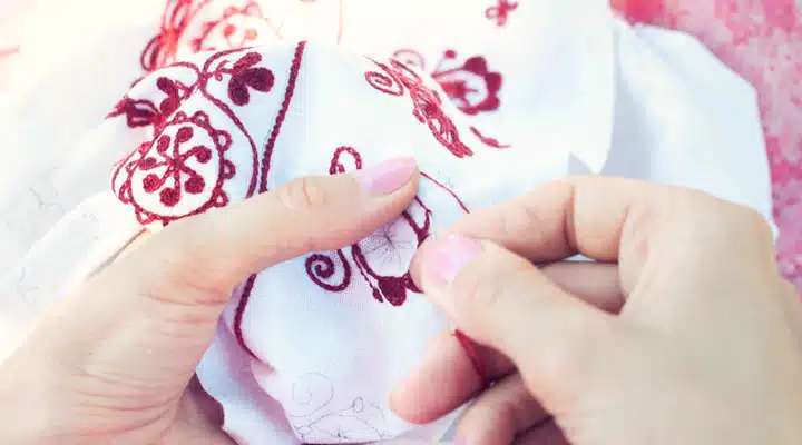 Woman Embroiders floral ornament on linen A hand holding a baby