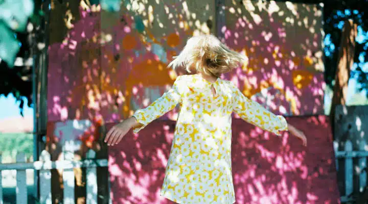 girl in yellow dress spinning on mixed shade and sun A person standing in front of a colorful dress
