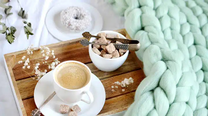 Cup with cappuccino, doughnutt, green pastel giant plaid, bedroo A plate of food and a cup of coffee