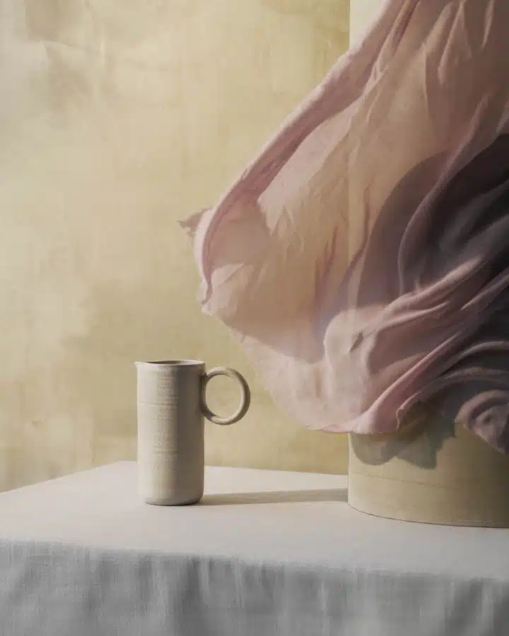 Nordic stilleben, Ceramics vase with windy curtain A person sitting on a bed