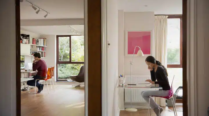 Couple working in bedroom and home office A person standing in front of a window