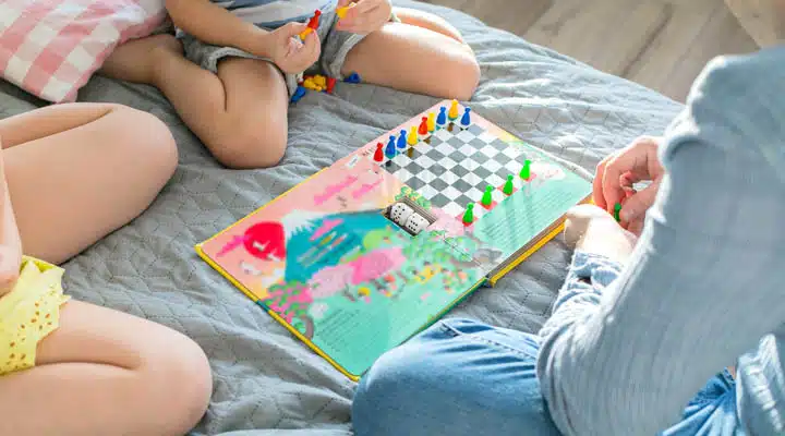 Father playing with daughter and son in board game. Concept of quarantine, pandemic, coronavirus, digital detox. Family staying at home. Self isolation. Corona virus epidemic A baby sitting on a bed