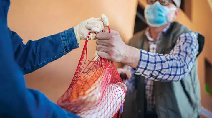 Teenage girl is delivering some groceries to an elderly person. A person holding a baby