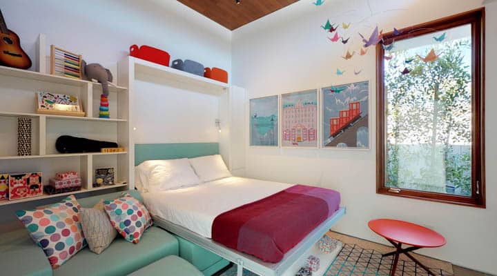 A bedroom with a bed and desk in a room