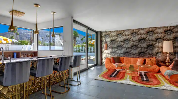 WET_BAR_TO_FAMILY_ROOM_WRAP_AROUND_MOUNTAINS-720x400 A bedroom with a bed and a chair in a room