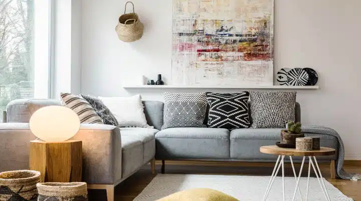 Yellow pillow and table on carpet in bright living room interior with light next to couch. Real photo A living room filled with furniture and a table