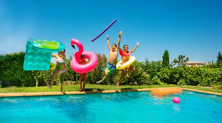 Joyful teens with swim tools jumping into the pool A group of people swimming in a pool of water