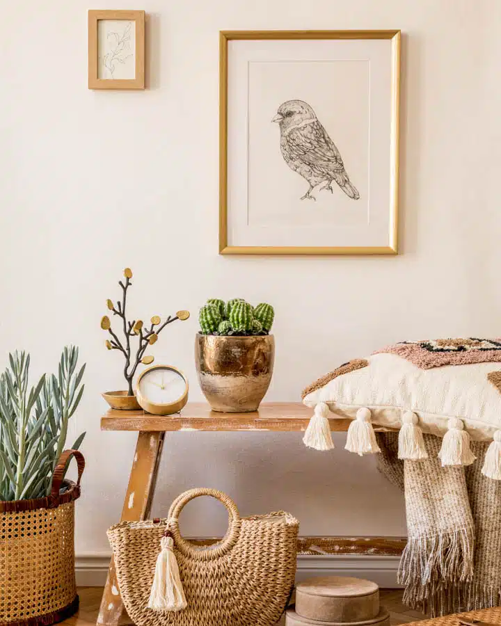 Stylish composition of living room interior with mock up frame, wooden bench, pillow, plaid, woman bag, plant, decortaion and elegant personal accessories in modern home decor. A room filled with furniture and vase of flowers on a table