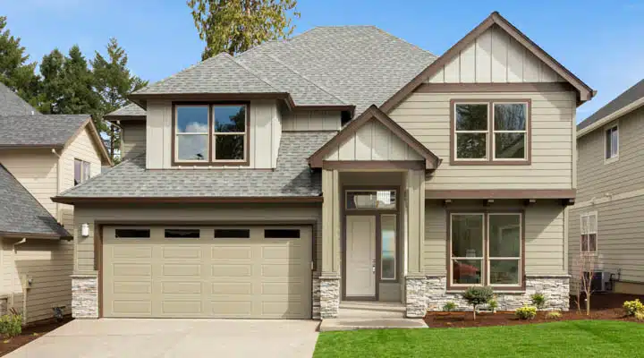 Exterior of new home on bright sunny day with blue sky A large brick building with grass in front of a house