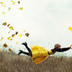 A person flying through the air while holding an umbrella