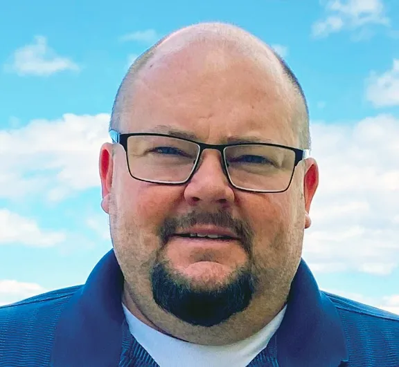 A man wearing glasses and smiling at the camera