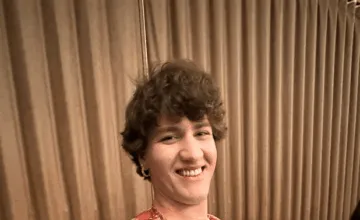 A person sitting in front of a curtain